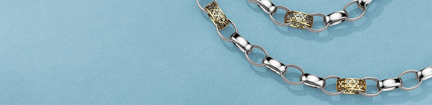 Birks Dare to Dream silver and gold link bracelet and necklace on a blue background.