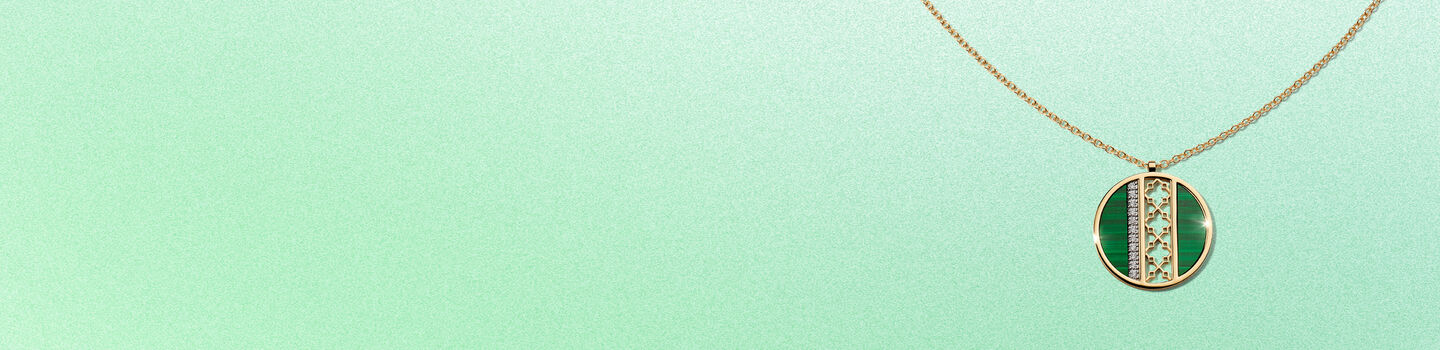 Un pendentif en or jaune et malachite Birks Dare to Dream sur un fond vert