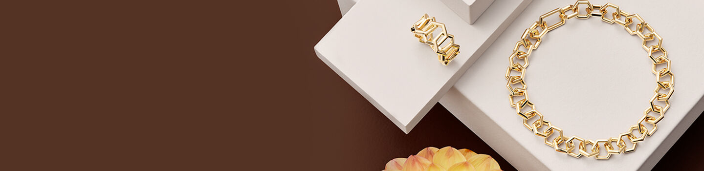 Bracelet et bague en or Birks Bee Chic posés sur des blocs blancs.