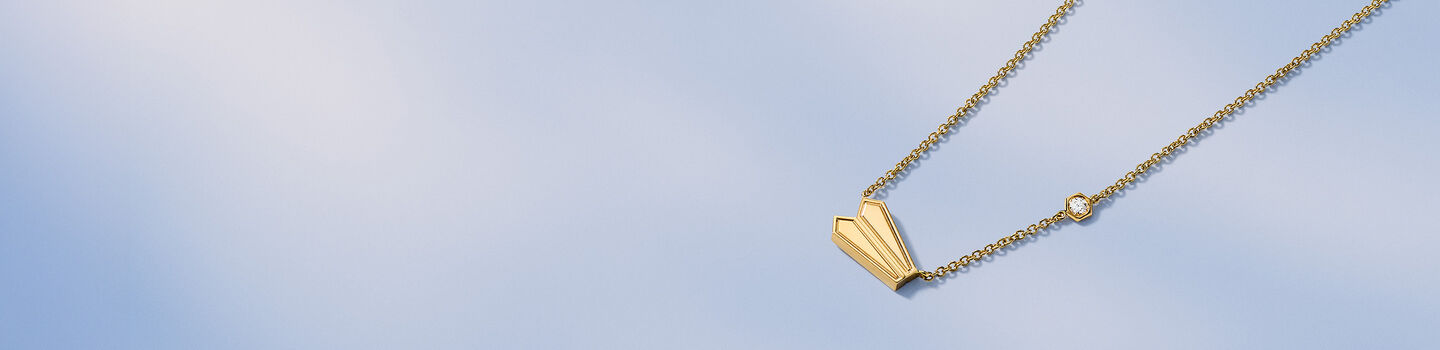 Birks Beekeeper yellow gold necklace on a blue background.