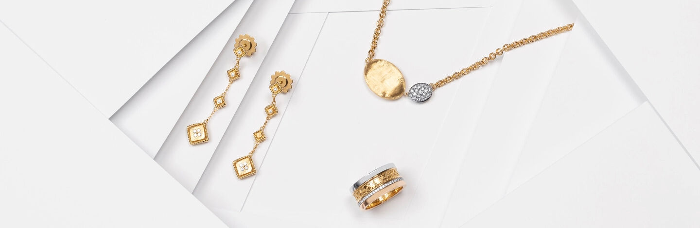 Roberto Coin gold earrings with a diamond and gold Marco Bicego pendant beside a Birks Dare to Dream tri-gold ring