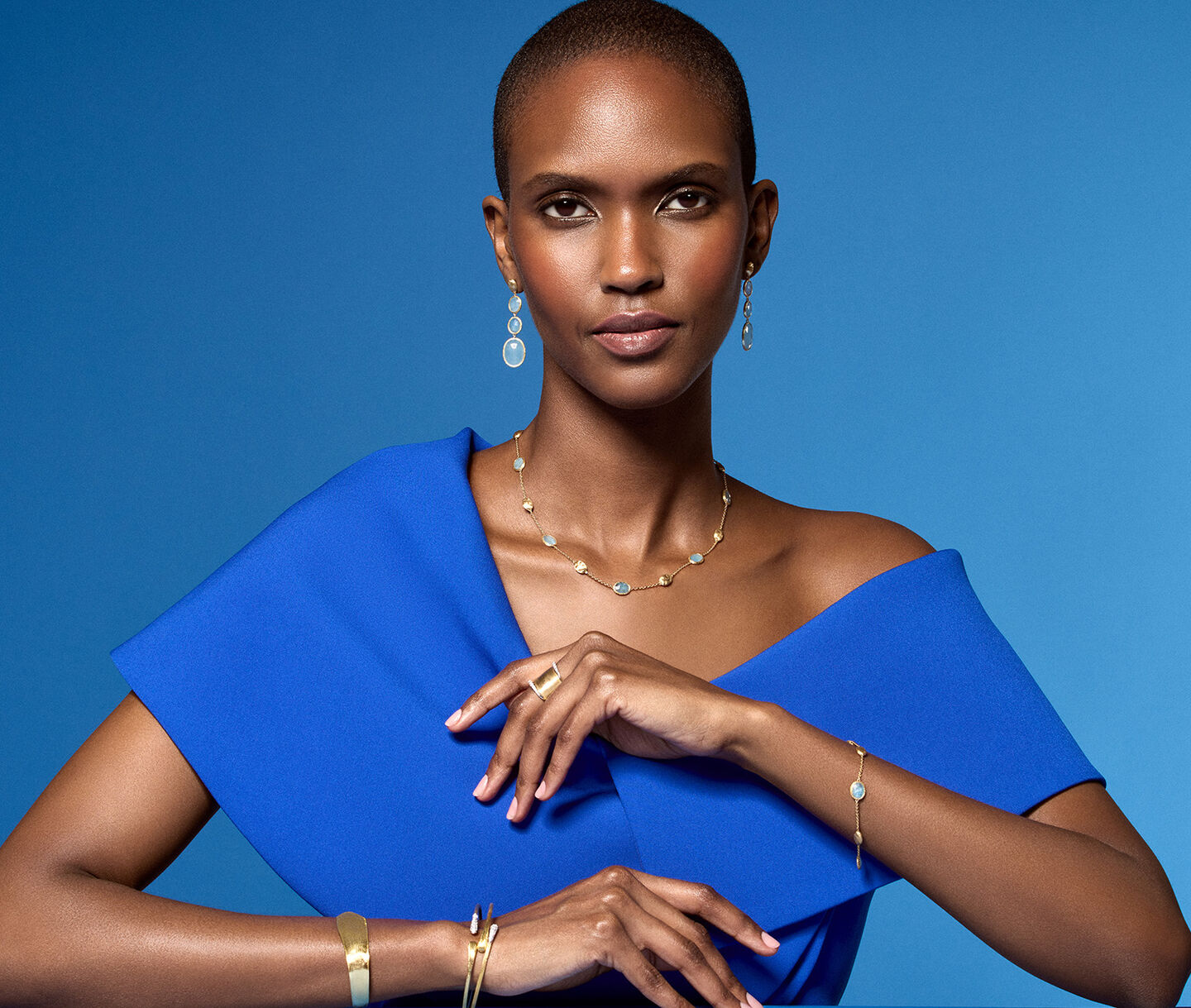 A woman wearing Marco Bicego jewellery on a blue background.