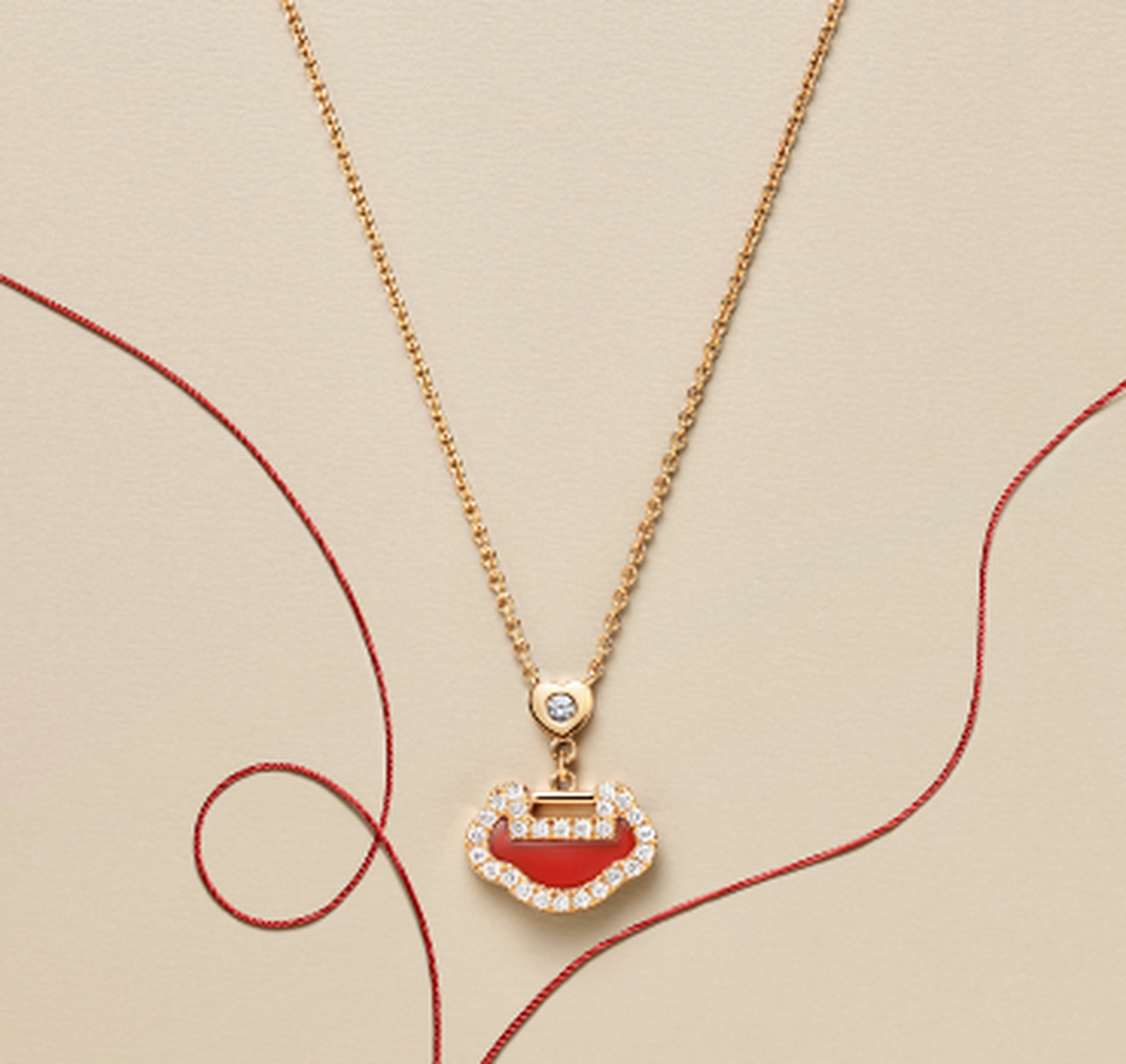 A Qeelin Yu Yi rose gold, red agate and diamond pendant on a beige background.