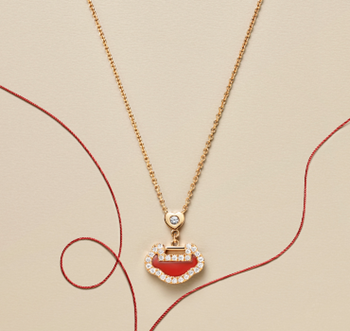 Un pendentif Yu Yi par Qeelin en or rose avec agate rouge et diamants sur un fond beige.