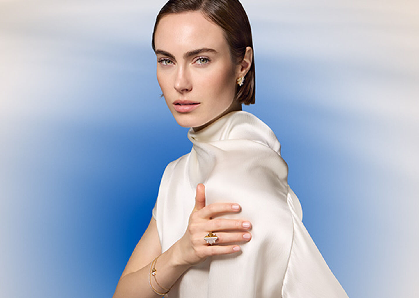 A woman wearing Maison Birks jewellery on a blue background.