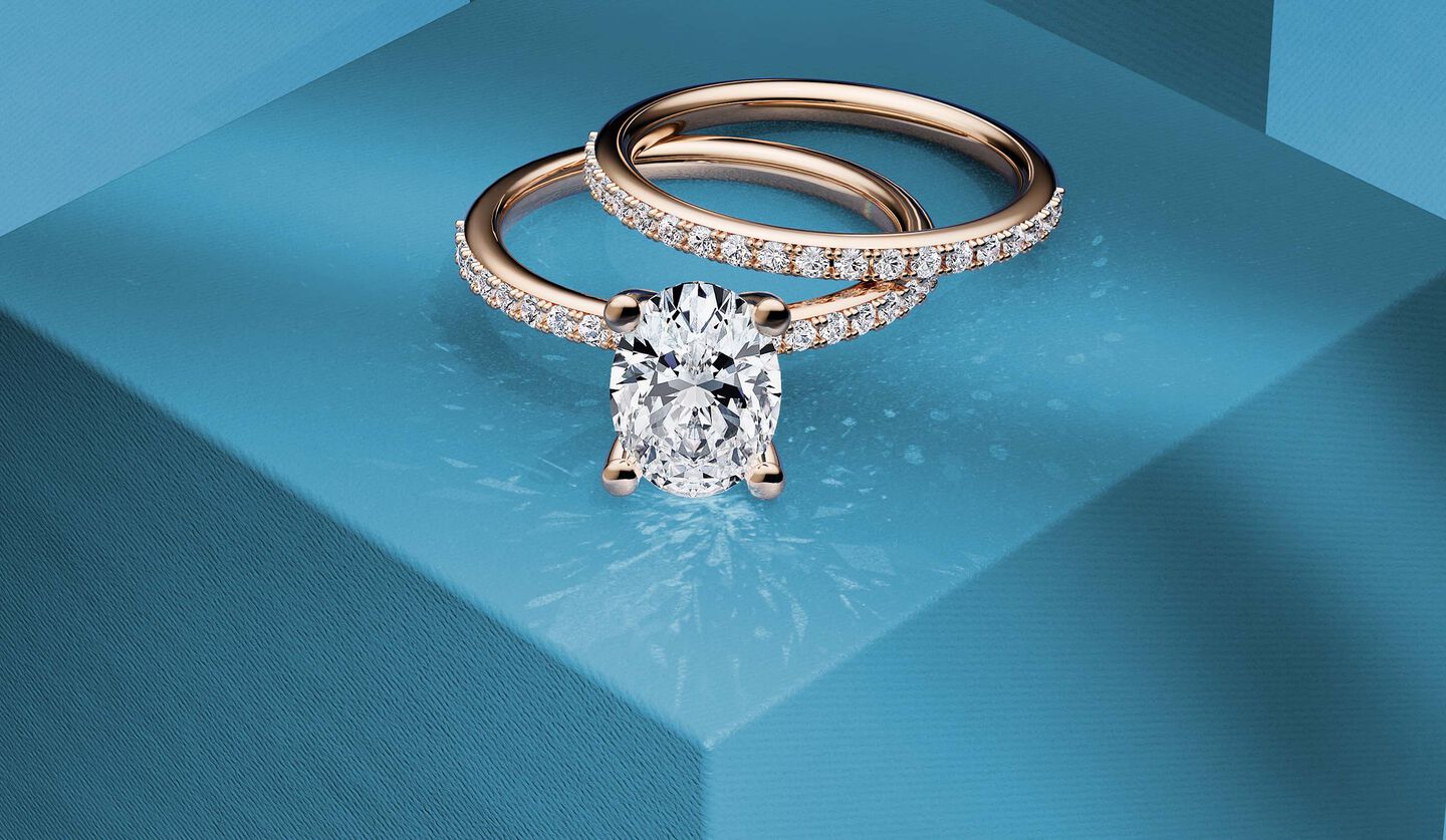 Bague de fian&ccedil;ailles &agrave; diamant solitaire en or rose avec alliance de mariage sur un fond bleu.