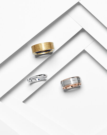 An assortment of wedding bands from Birks on a white layered background.