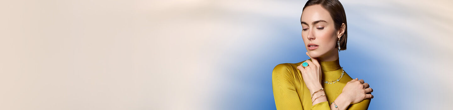 A woman wearing Maison Birks jewellery on a blue background.