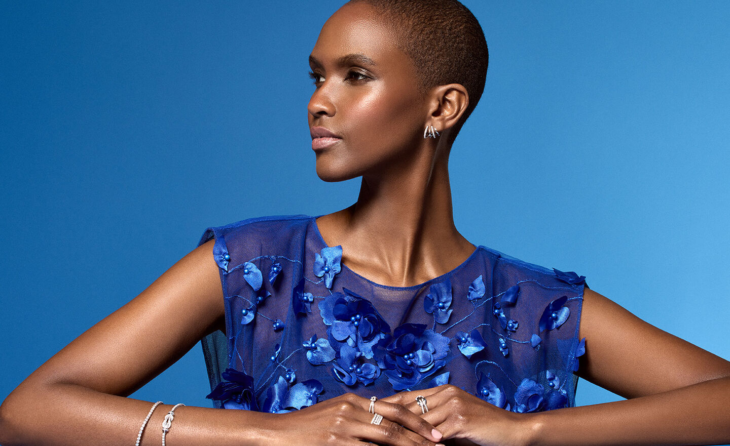 A woman wearing diamond jewellery from Maison Birks on a blue background.