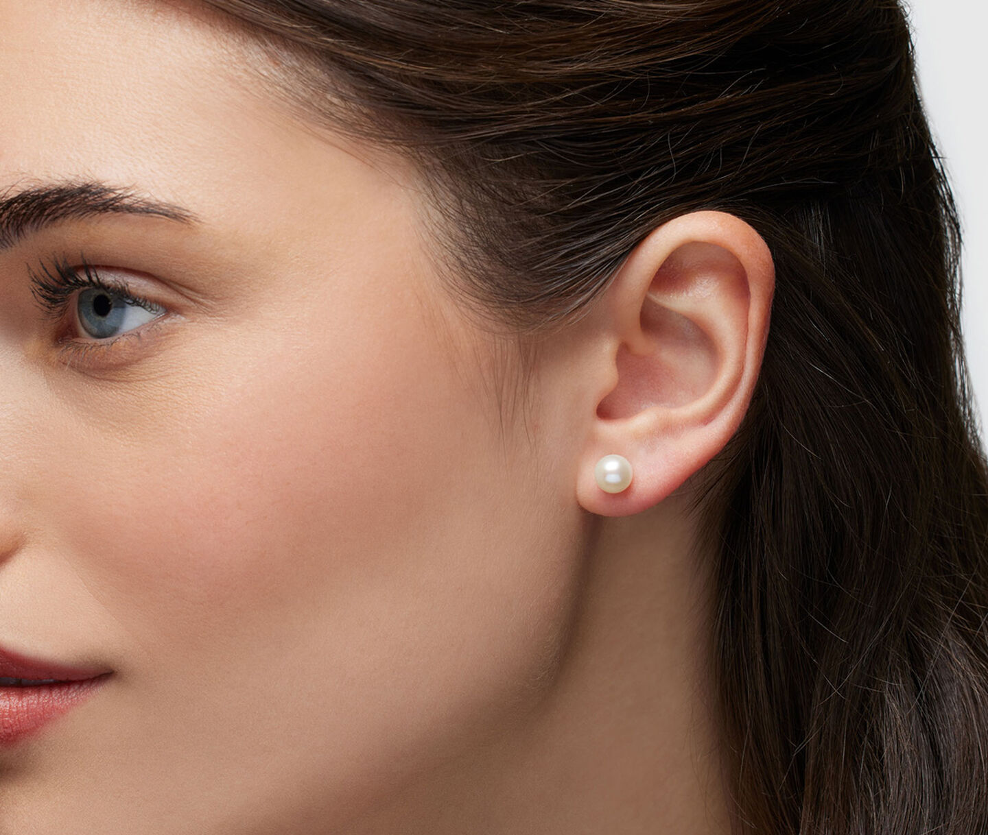 A woman wearing Birks Pearl stud earrings.