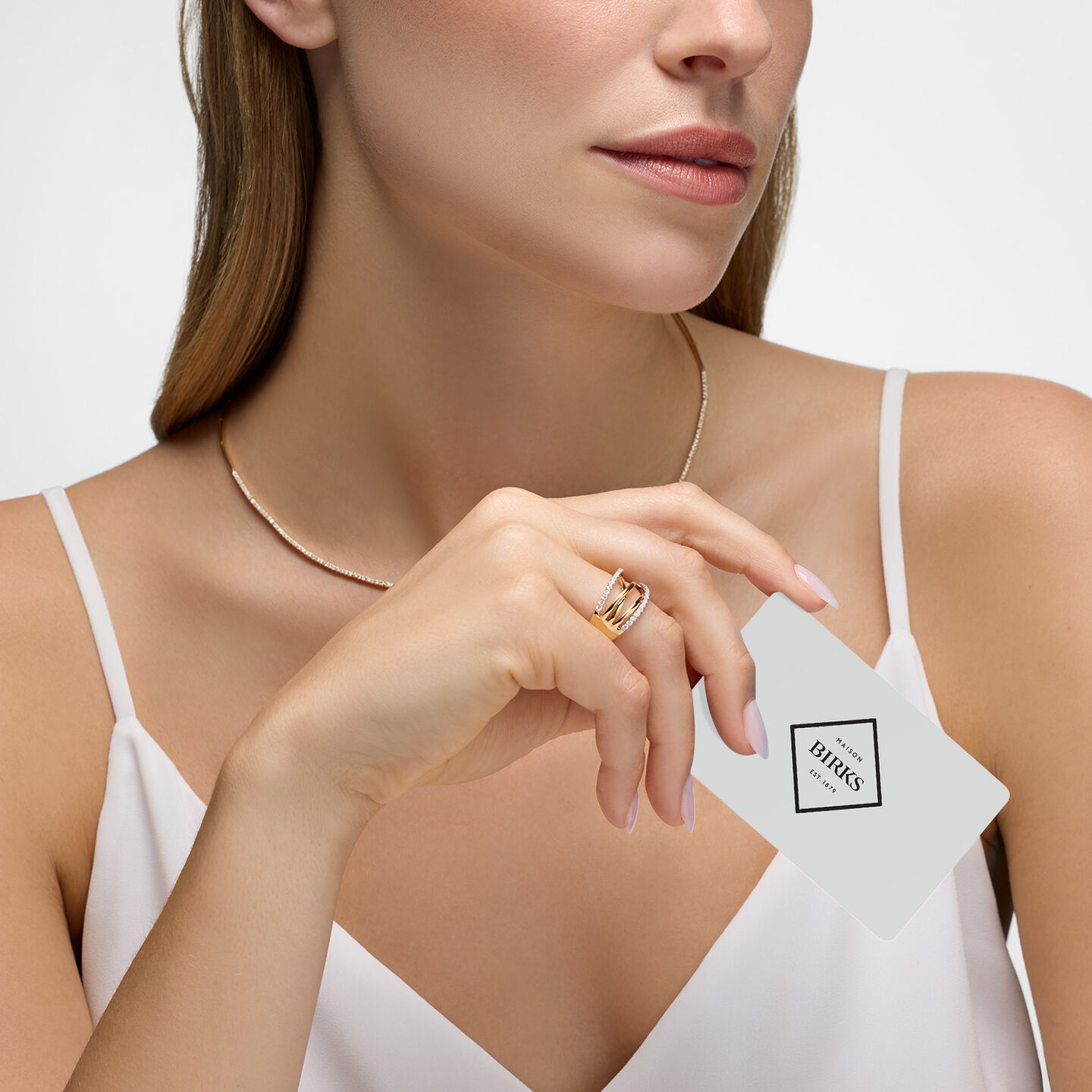 A woman holding a Maison Birks gift card.