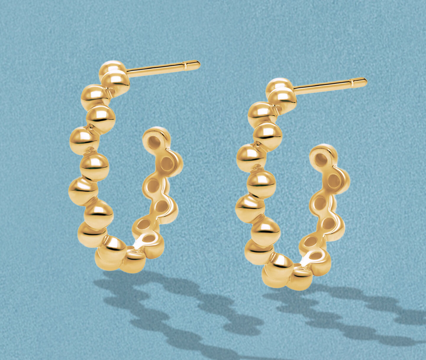 Boucle d&rsquo;oreille Birks Iconic Splash en or jaune sur fond bleu.
