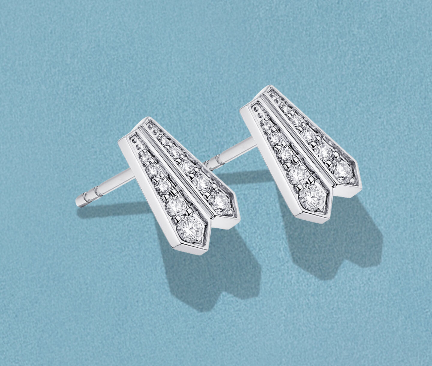 Boucles d'oreilles Birks Beekeeper avec diamants sur un fond bleu.