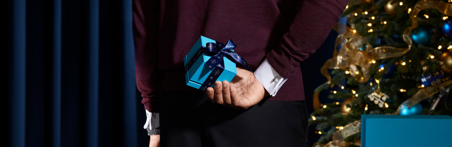 A man holds a Birks blue box behind his back.
