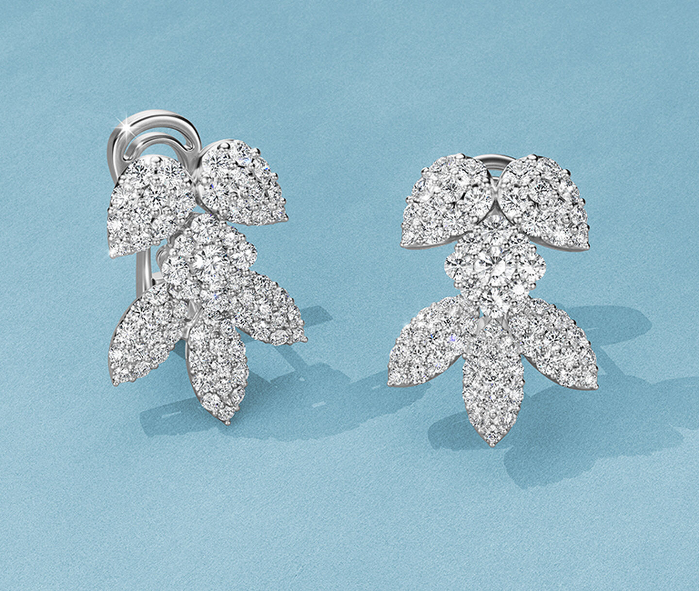 Birks Snowflake diamond earrings on a blue background.