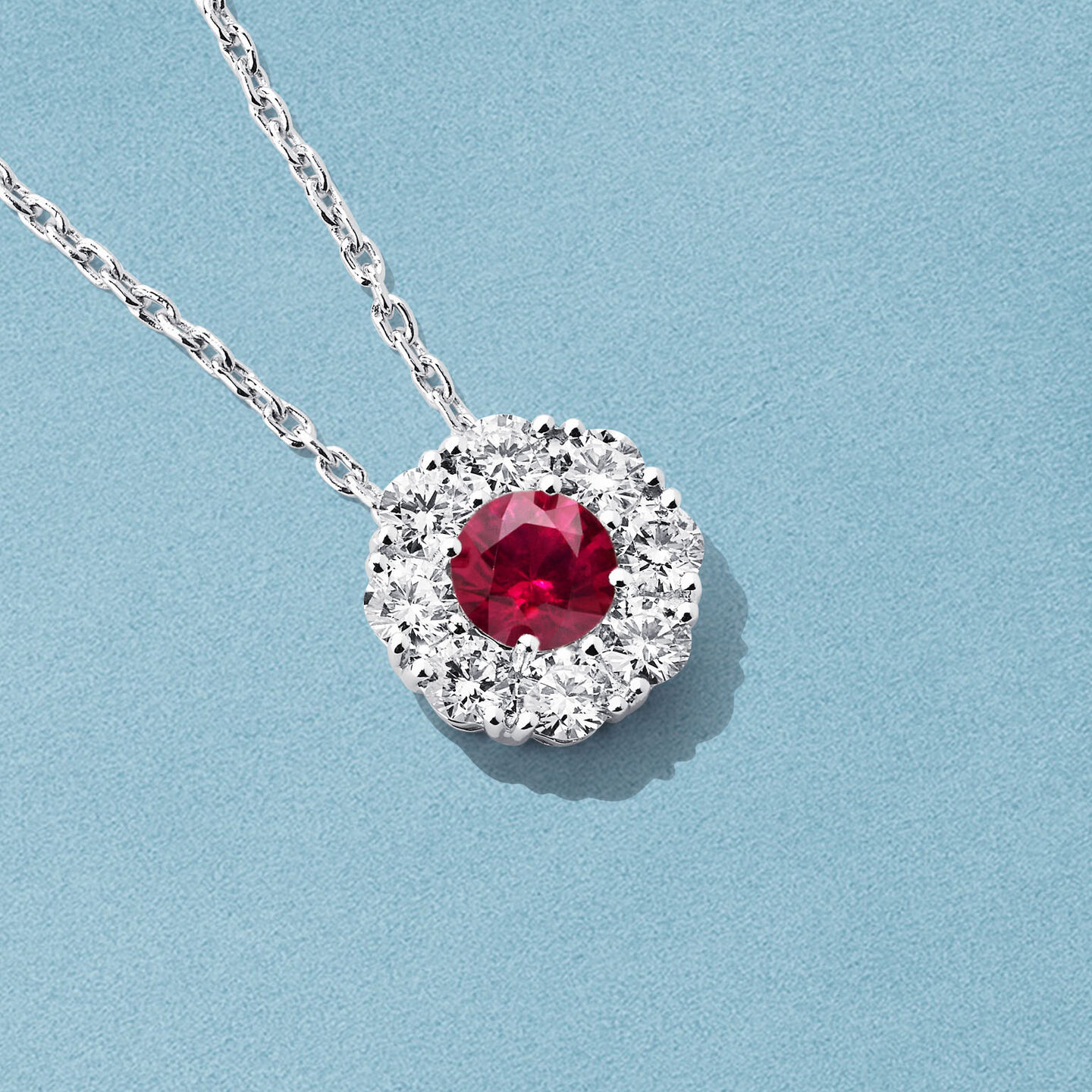 Collier Birks Snowflake avec rubi et diamants sur un fond bleu.