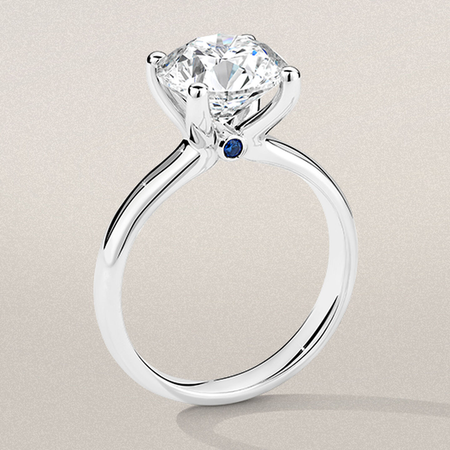 Birks Blue Diamond Engagement Ring with Sapphire Accent on a beige background.