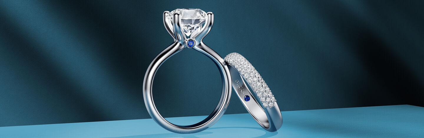 Birks Blue diamond engagement ring and wedding band on a blue background.