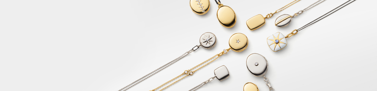Monica Rich Kosann Lockets on a greyish background