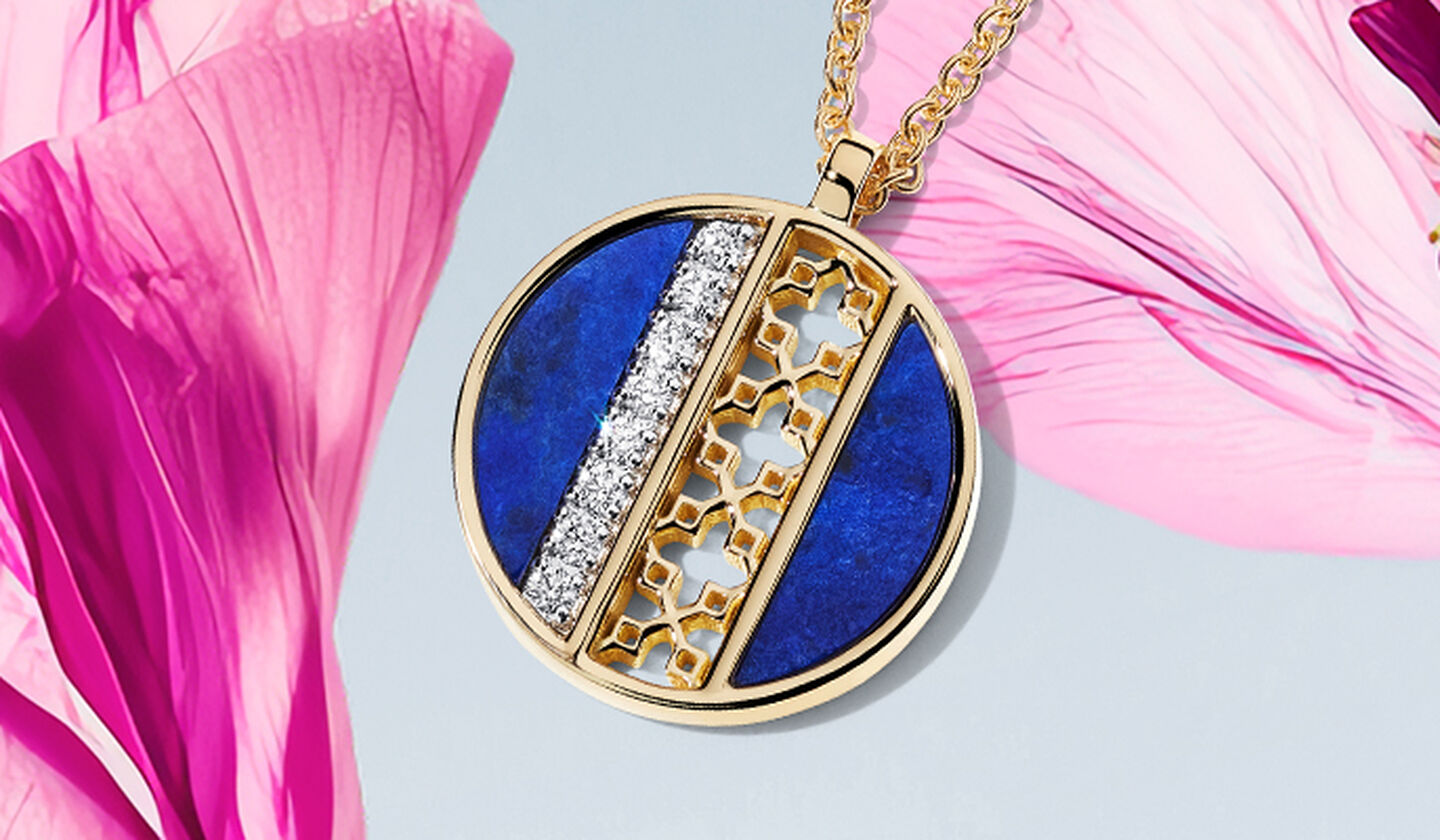 Un médaillon Birks dare to dream en lapis-lazuli et diamants sur fond bleu ciel clair de fleurs roses.