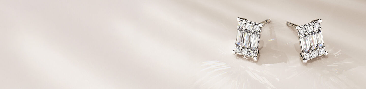 Birks Essentials diamond cluster earrings on a beige background.