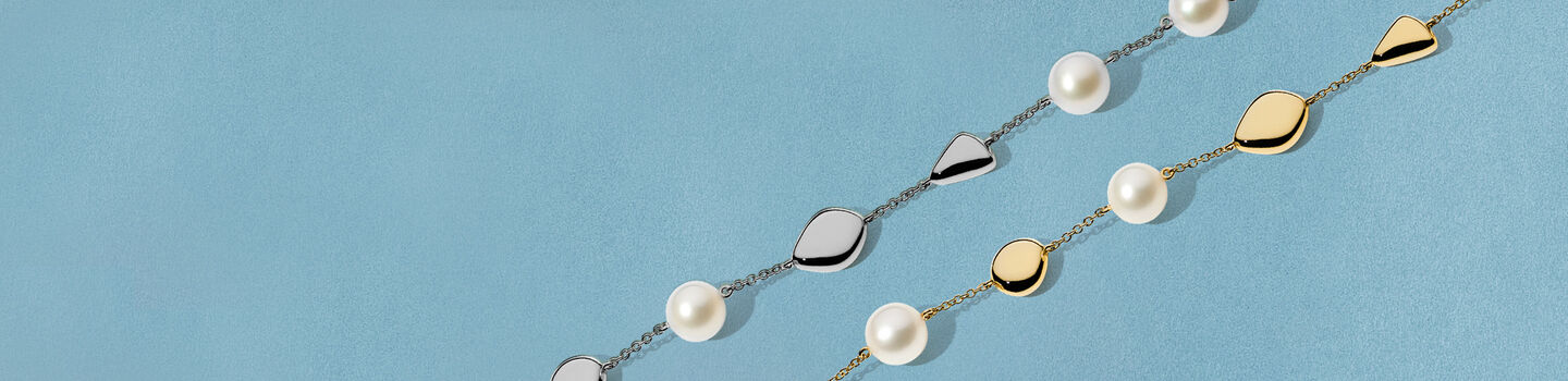 Bracelets Birks Pebble en or jaune et argent avec perles sur un fond bleu.