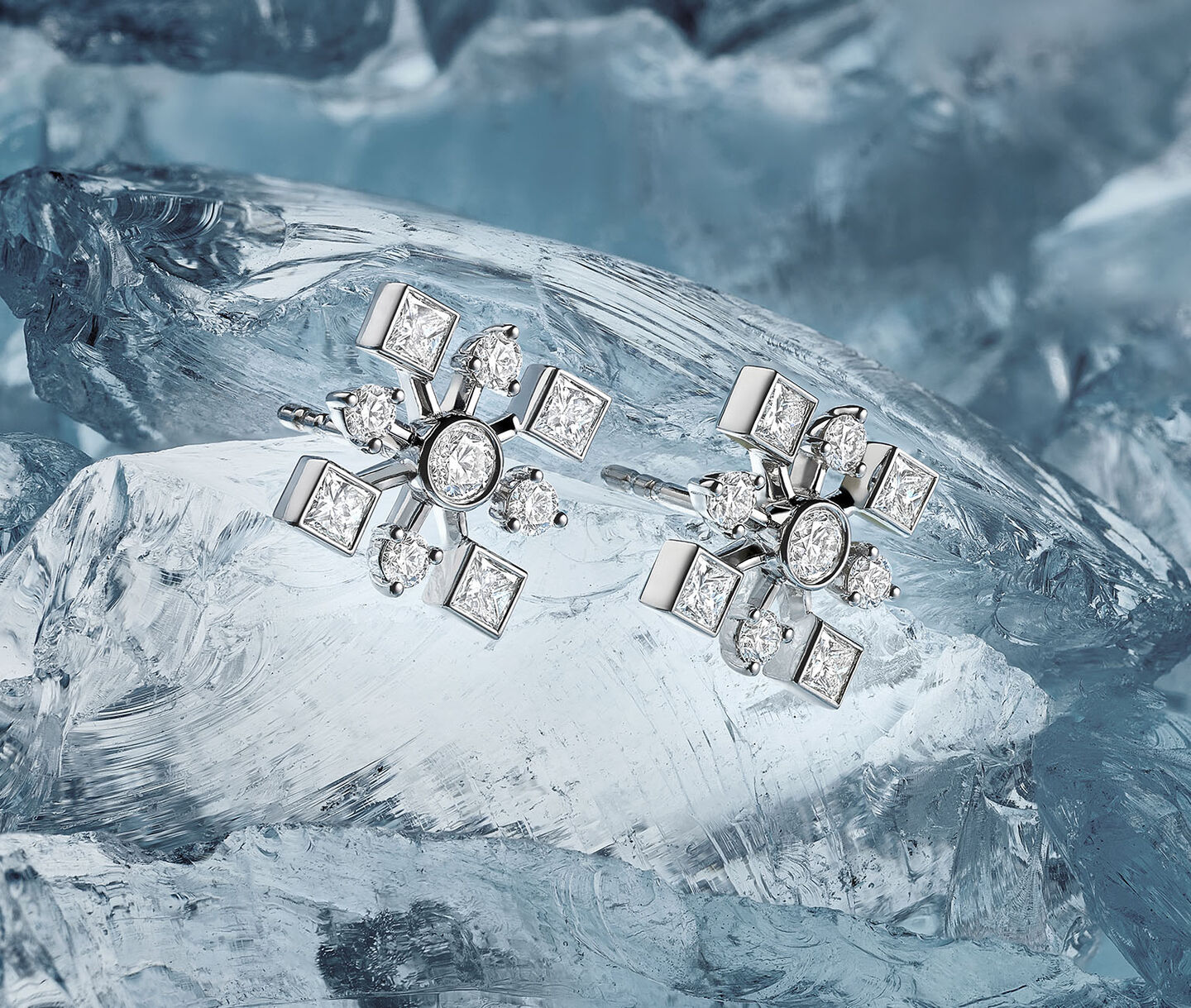 Boucles d'oreilles Birks Snowflake avec diamants sur un fond enneigé.
