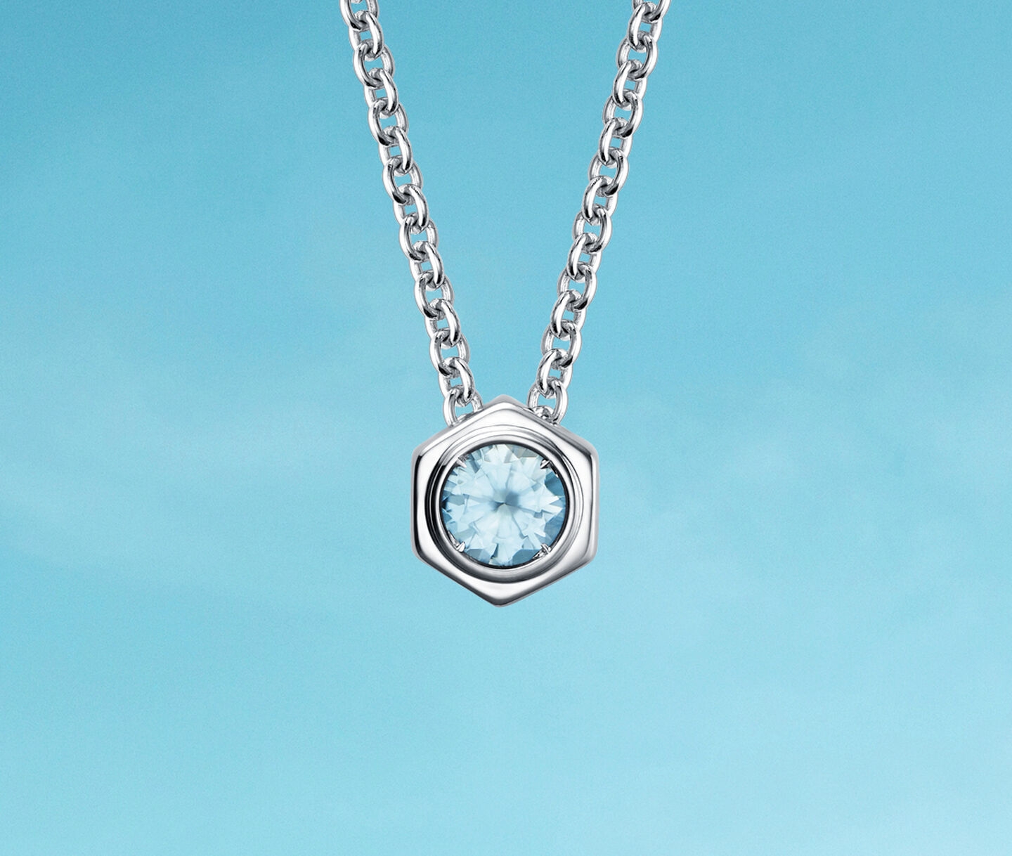 Birks Bee Chic aquamarine birthstone necklace on a blue background.