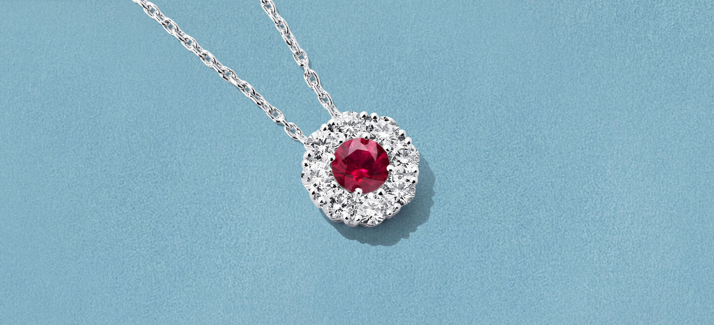 Collier Birks Snowflake avec rubi et diamants sur un fond bleu.