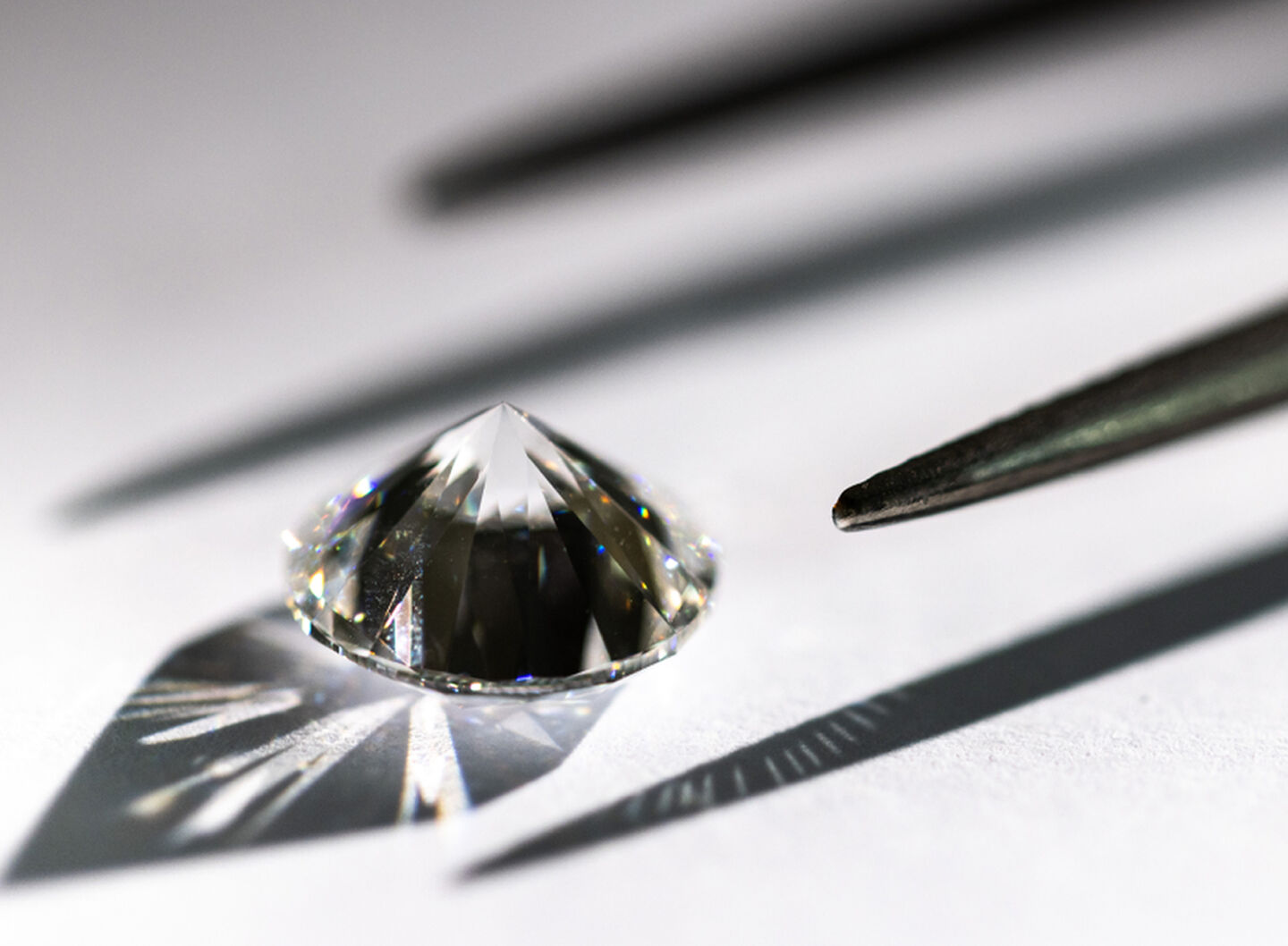 Gros plan d’un diamant Birks avec pince sur surface blanche.