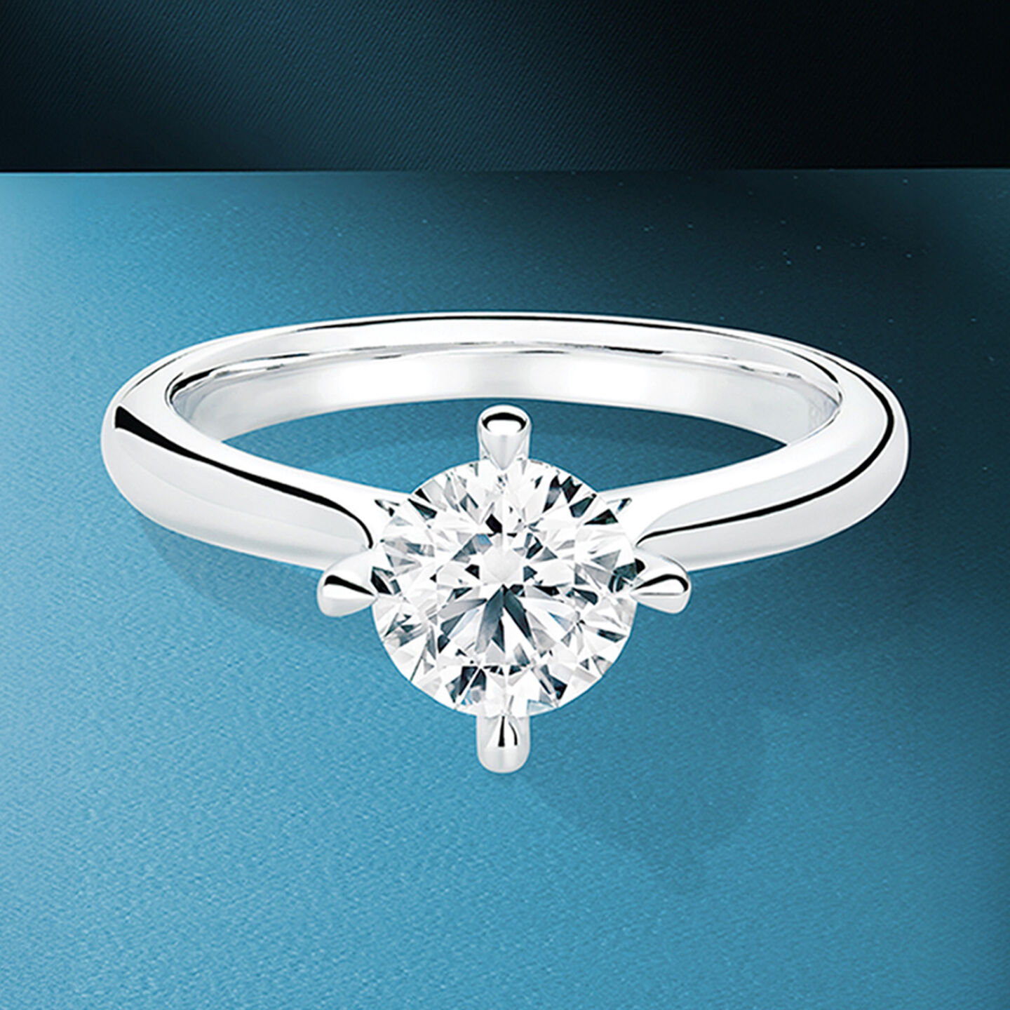 Birks diamond solitaire pendant on a blue background.
