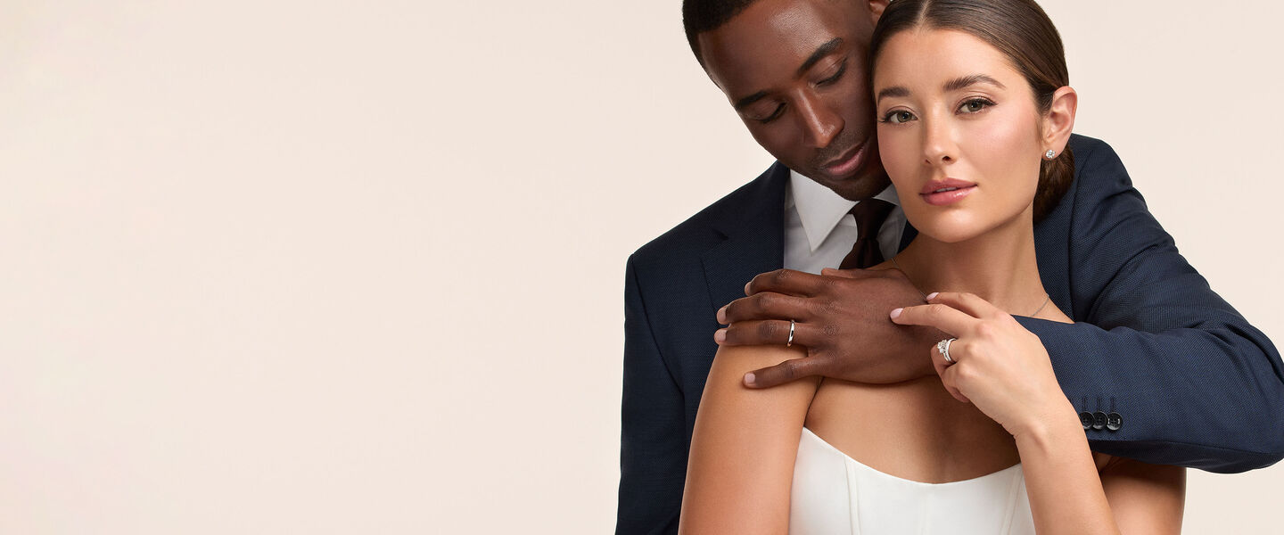 A couple embracing on their wedding day wearing Birks wedding jewellery.