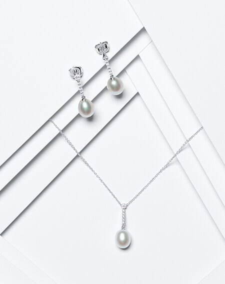 Birks Pearls drop earrings and pendant on a white layered background.