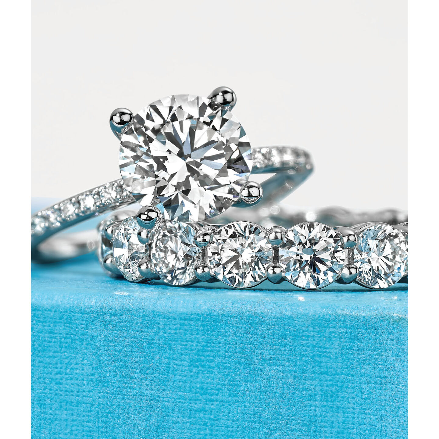 A Birks engagement ring and wedding band sit on a blue box.
