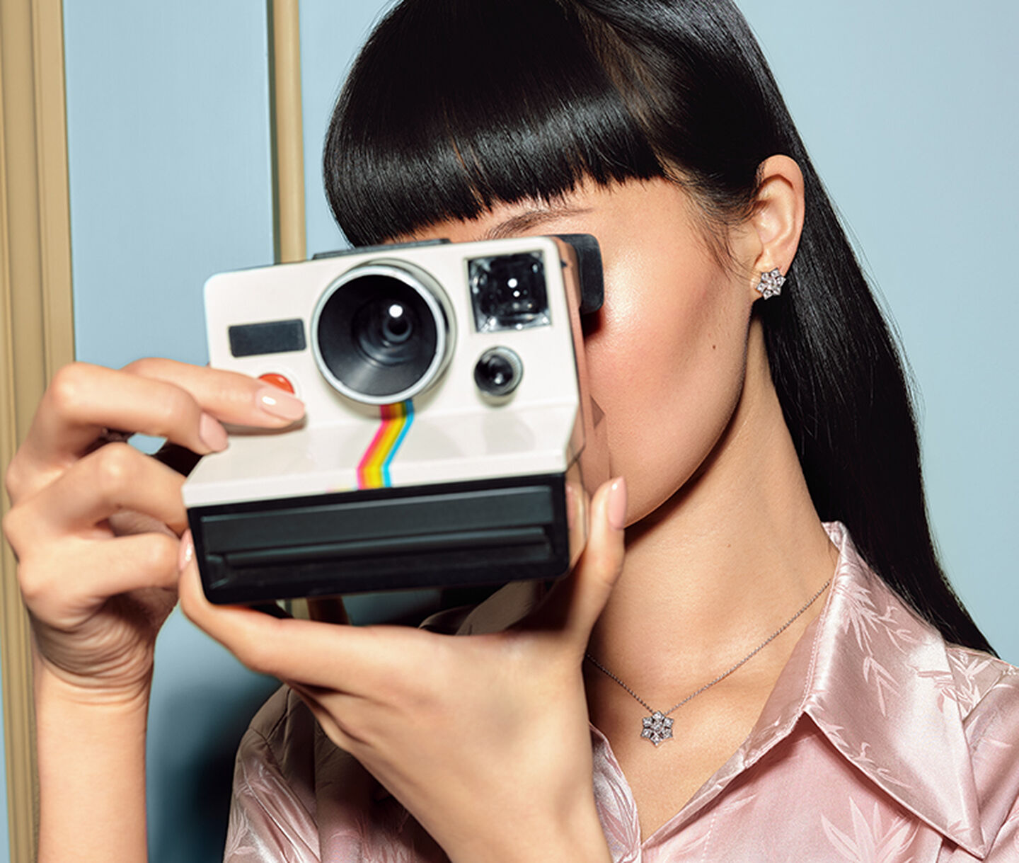 A woman holding a camera wearing Birks Snowflake diamond jewellery.
