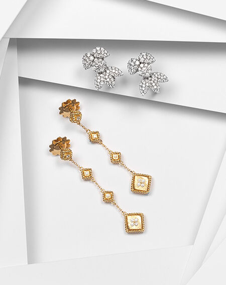Boucles d'oreilles pendoloques en or jaune de Roberto Coin avec les boucles d'oreilles en diamants Birks Snowflake sur un fond blanc