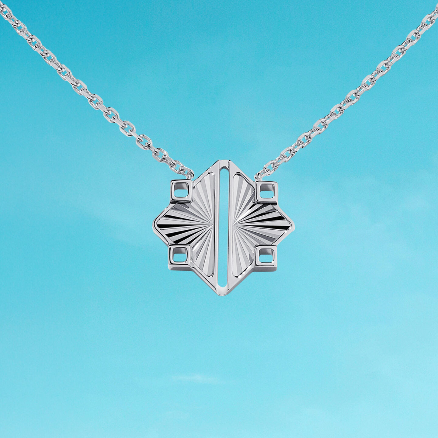 Birks Muse silver pendant on a blue background.
