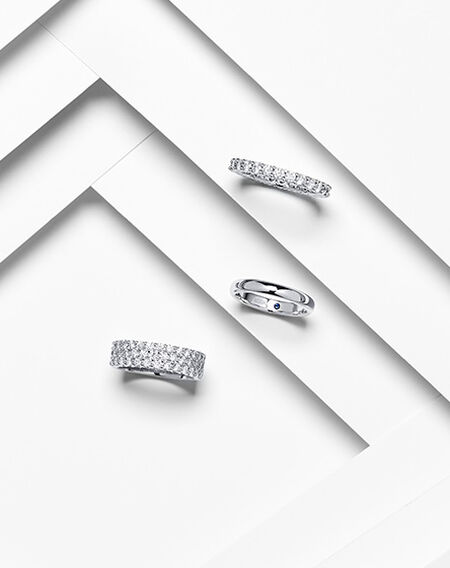 An assortment of women's wedding bands from Birks on a white layered background.