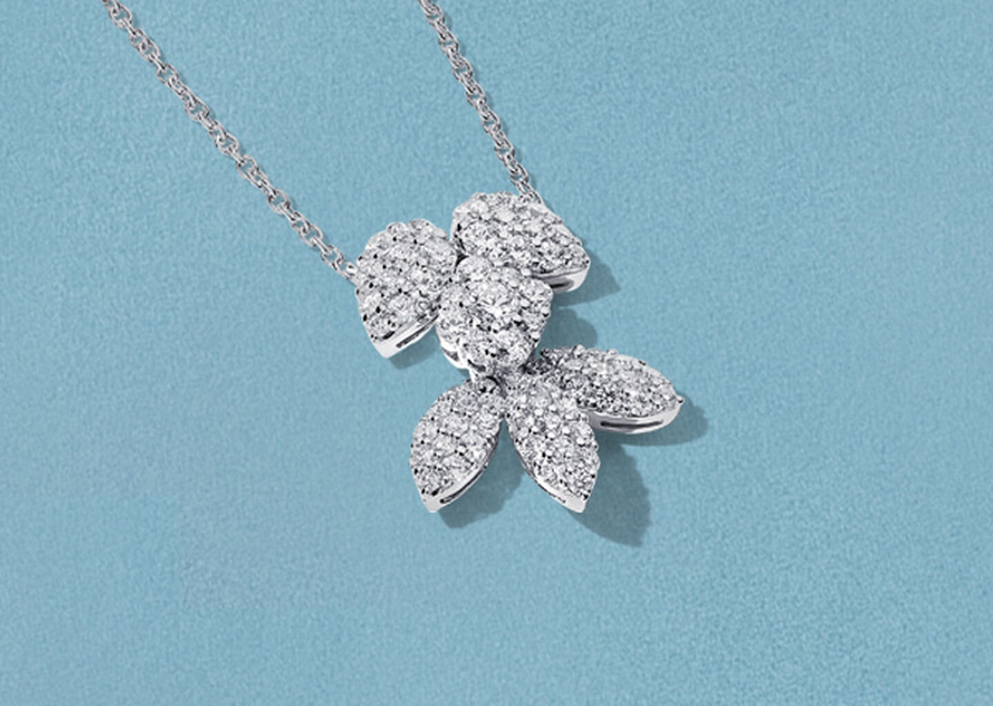 Birks Snowflake diamond necklace on a blue background.