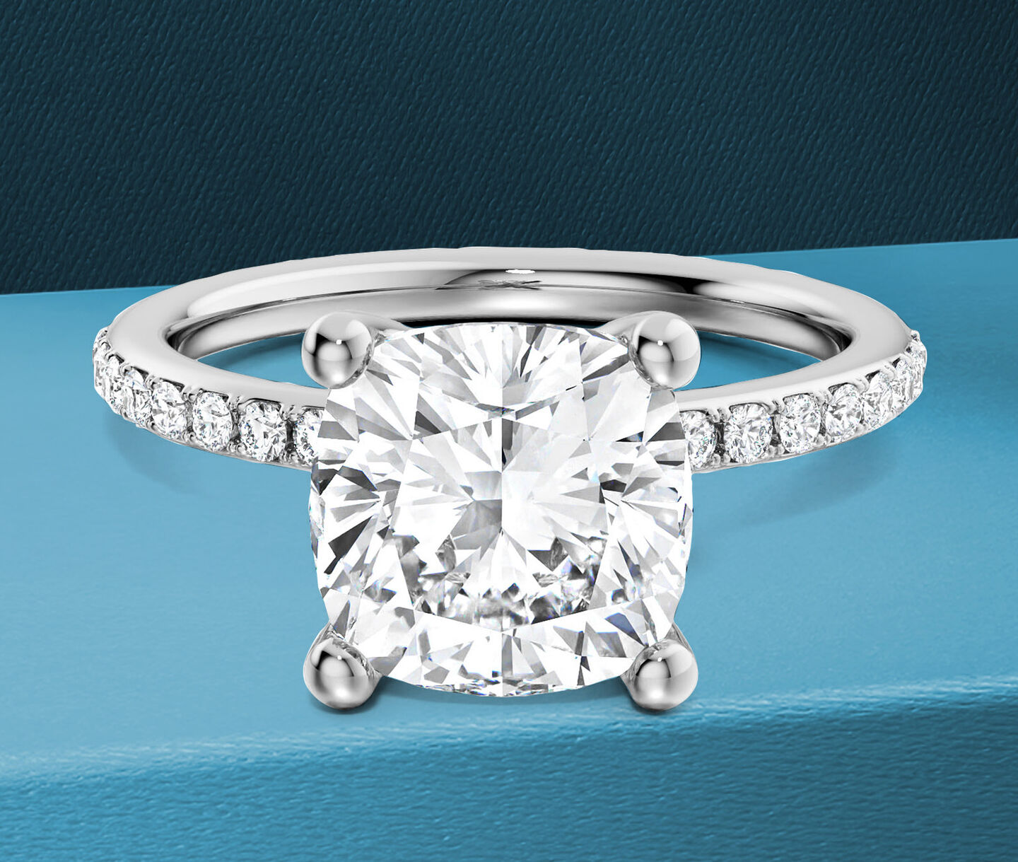 Birks Ros&eacute;e du Matin cushion diamond engagement on a blue background.