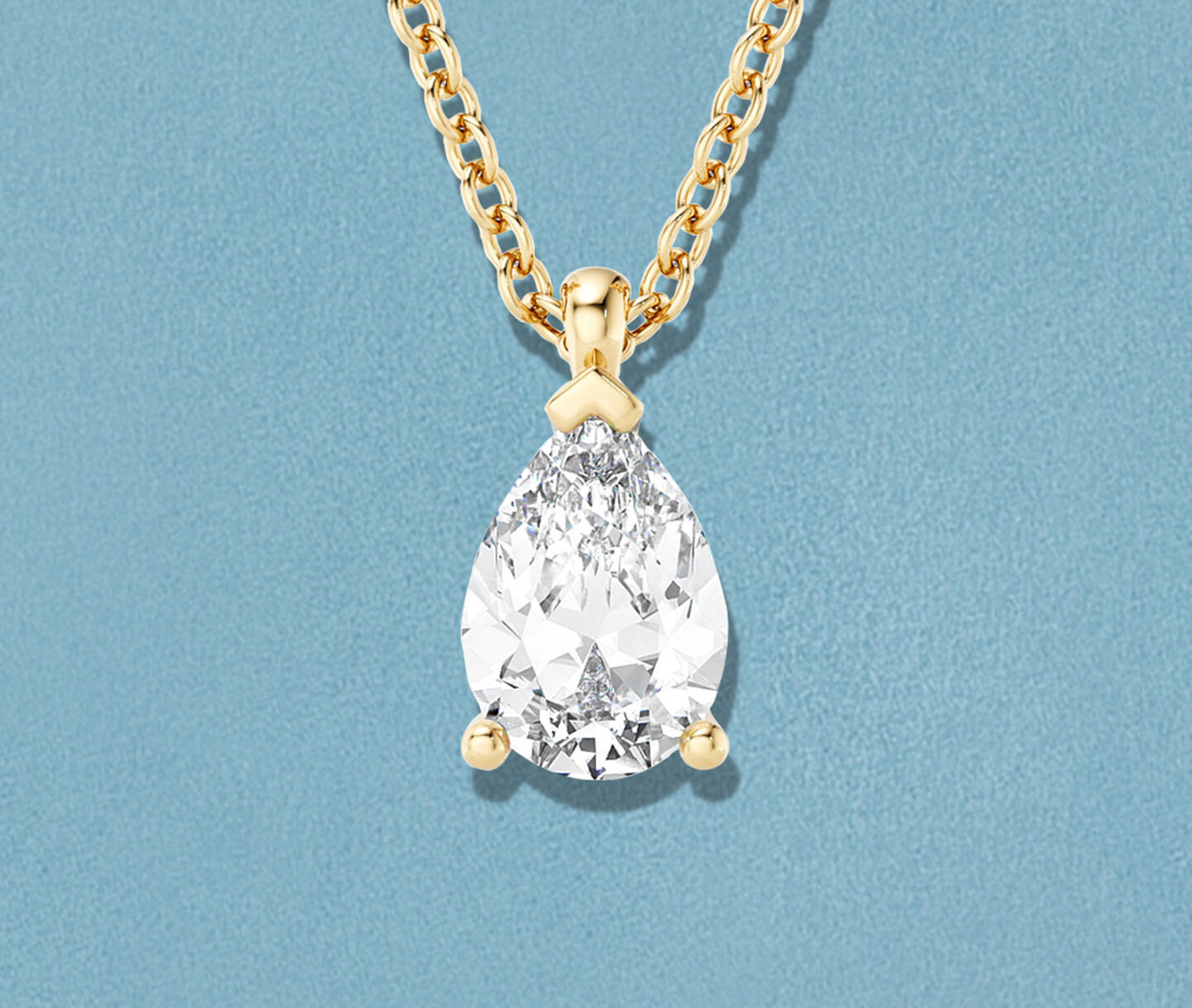 Birks Blue pear-cut diamond pendant necklace on a blue background.