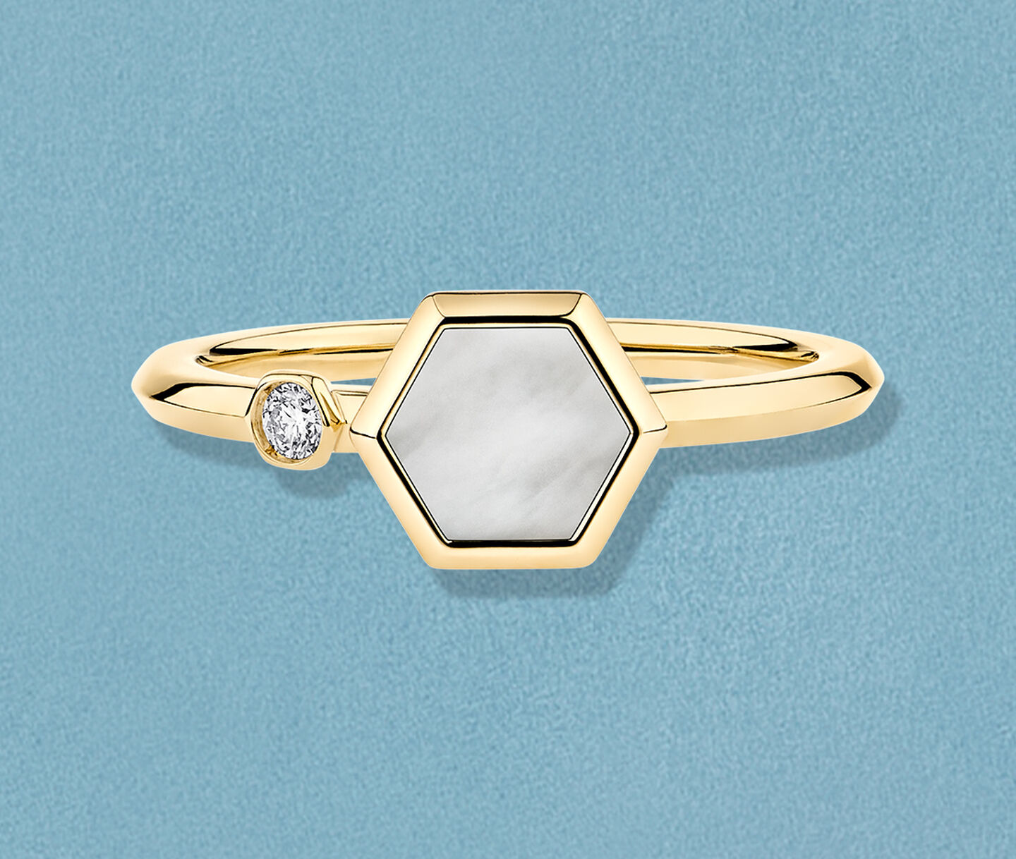 Birks Bee Chic yellow gold and mother-of-pearl ring on a blue background.