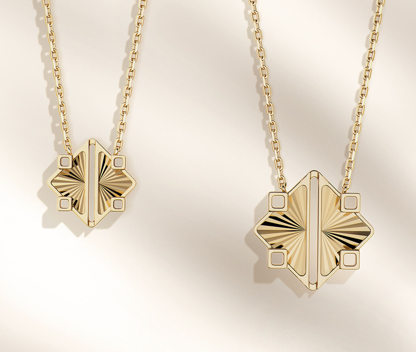 Two Birks Muse yellow gold pendants on a beige background.