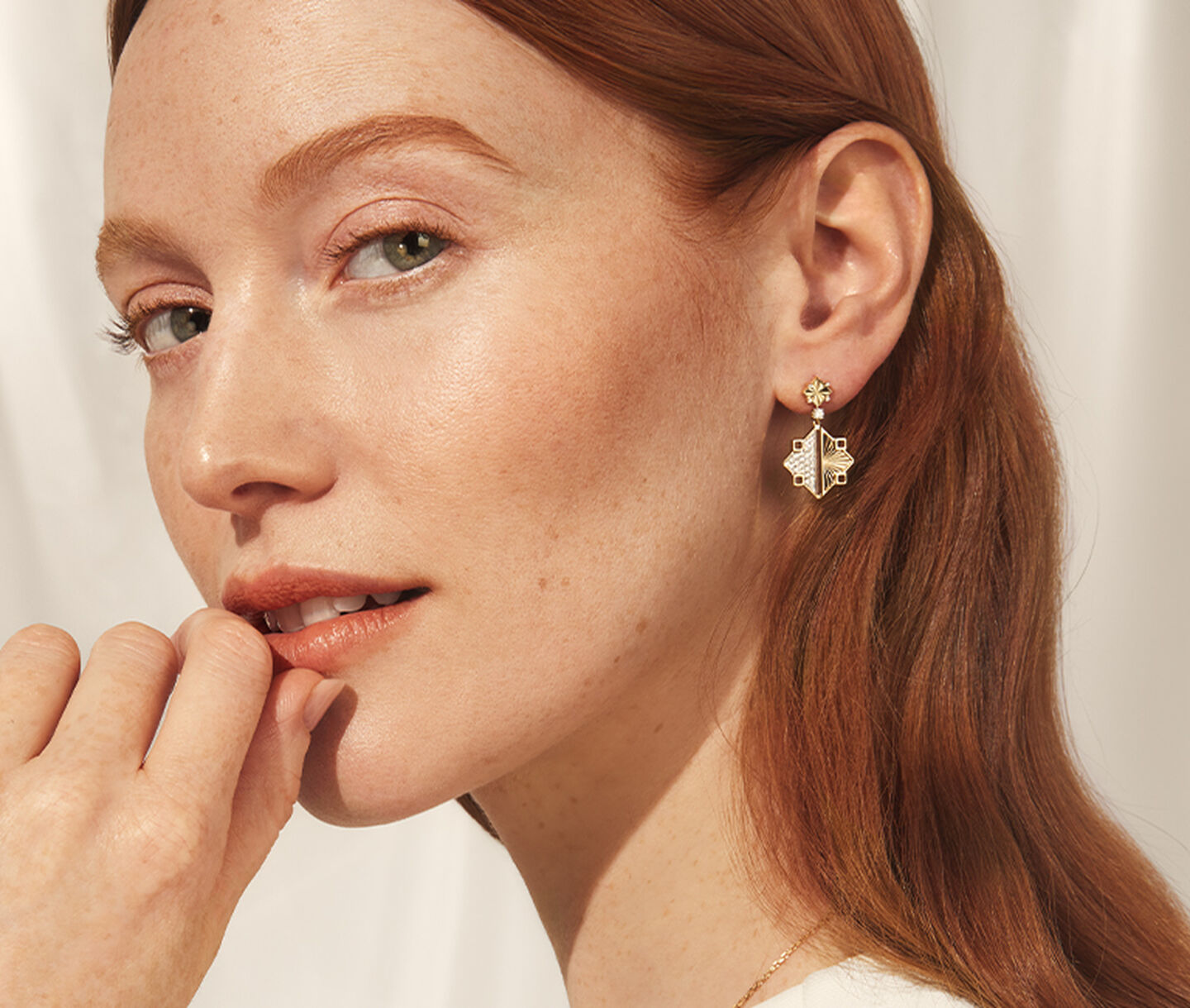 A woman wearing Birks Muse gold drop earrings.
