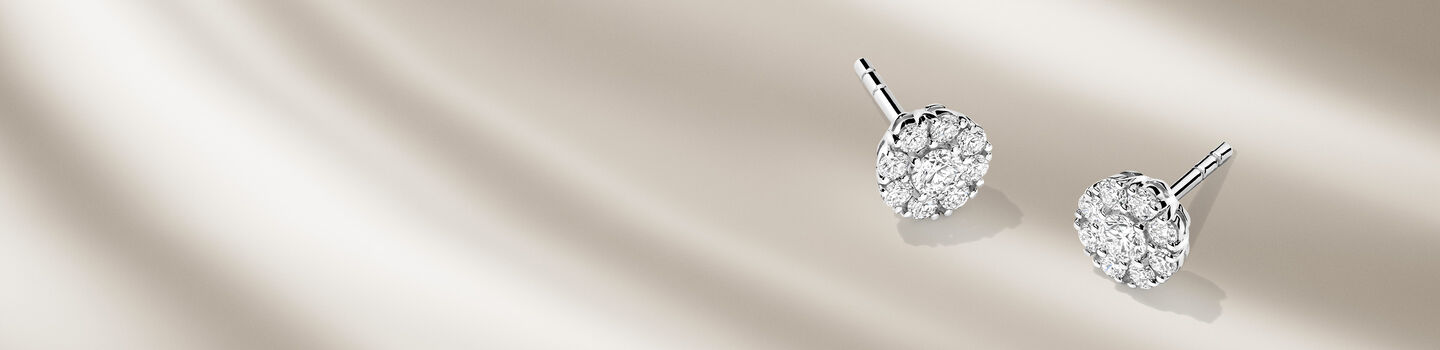 Birks Snowflake diamond cluster earrings on a beige background.