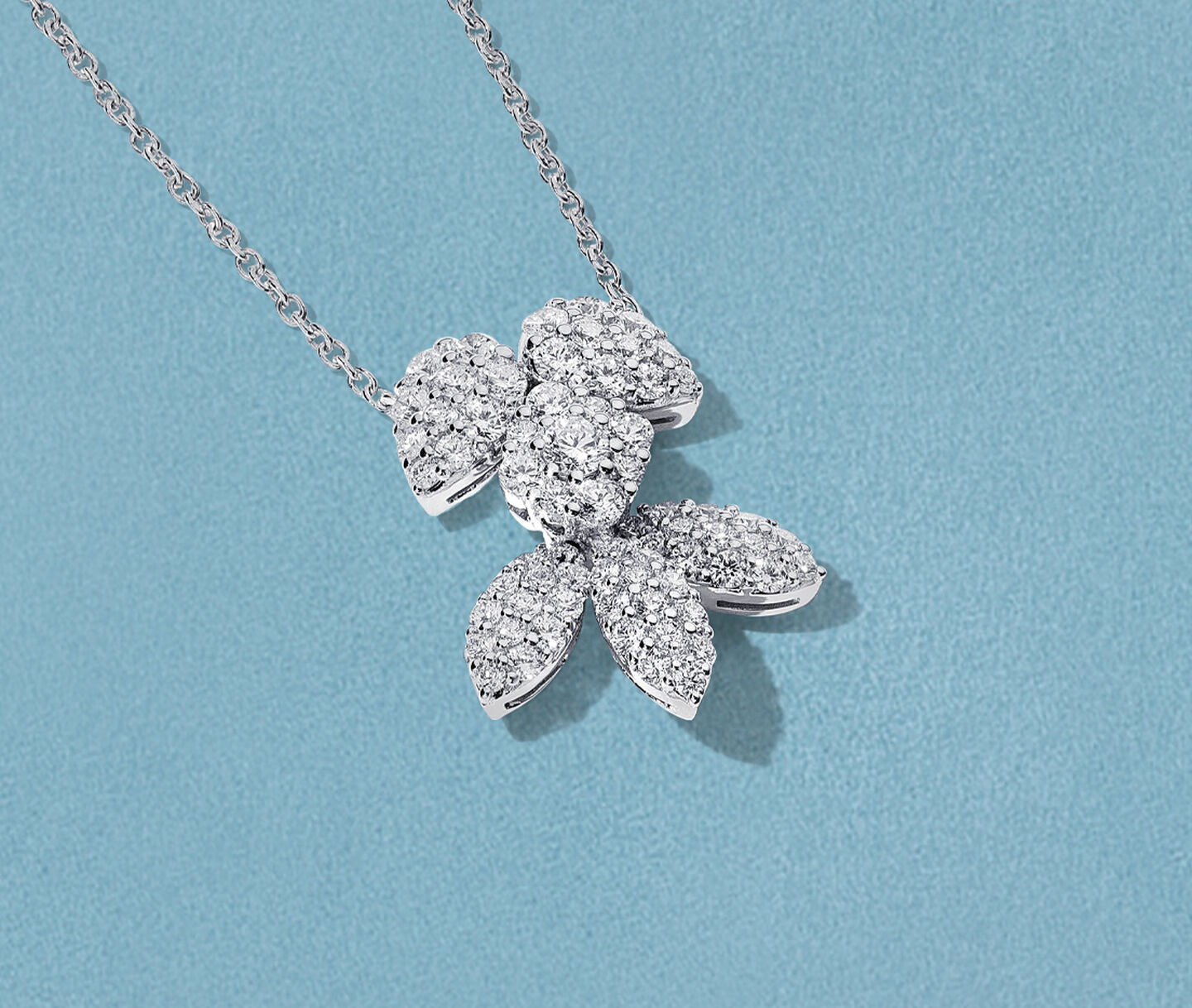 Birks Snowflake diamond pendant on a blue background.