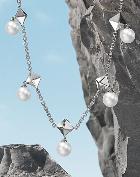 Birks Rock and Pearl silver necklace on a  grey rock mountain and blue background
