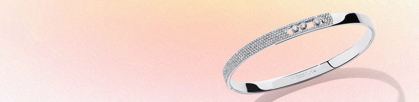 Messika white gold and diamond bangle on a pink background.