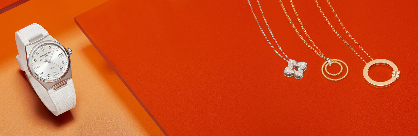 Three Gold pendant necklaces next to a white and silver watch