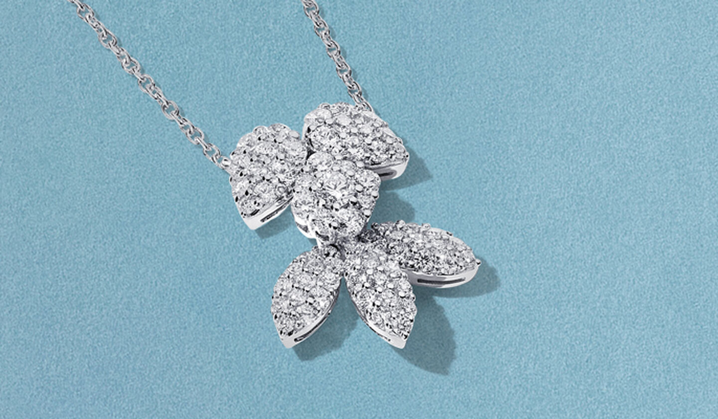 Collier Birks Snowflake en or blanc et diamants sur fond bleu.
